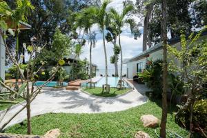 甲米镇BeachHouse Pool Villas Krabi的一个带游泳池和棕榈树的后院