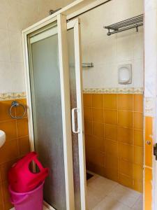 巴加Holidays Beach Apartments Goa的浴室设有淋浴门和粉红色垃圾桶。