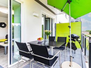 宾茨FeWo Prora - Have a nice Day的阳台配有桌椅和绿色遮阳伞