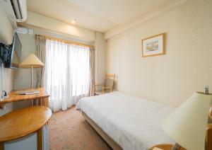 东京Saka no Hotel Tretio Ochanomizu的配有一张床、一张书桌和一扇窗户的酒店客房
