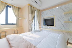 雅加达RedLiving Apartemen Jakarta Living Star - BoboRooms的卧室配有一张白色大床和电视。