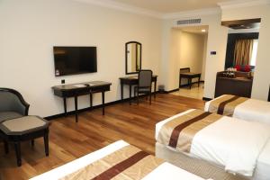 关丹Grand Darul Makmur Hotel Kuantan的酒店客房配有两张床和一张书桌