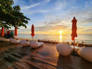 Ban Phang PhraoYotaka Khanom的海滩上带遮阳伞的木甲板,享有日落美景