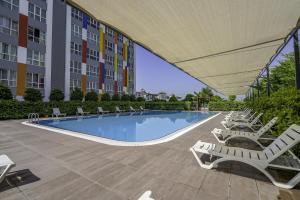 安塔利亚Residence w Shared Pool 3 min to Mall of Antalya的一座带躺椅的游泳池和一座建筑