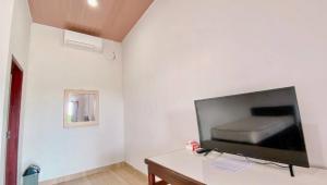 RatodenaAmadeo Guest House的一间客厅,在白色的墙上配有电视