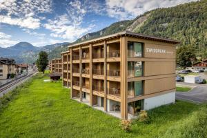 迈林根SWISSPEAK Resorts Meiringen的山前带绿色草坪的公寓楼