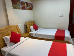 BhadrāvatiSTAYMAKER DV Residency的红色和白色的客房内的两张床