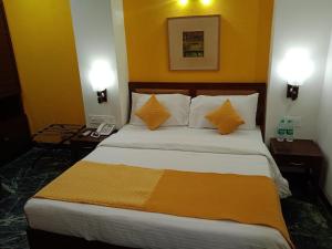 新德里The Corus Hotel的一间卧室配有一张大床、两张桌子和两盏灯。