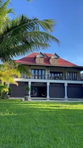 马埃岛Paradise Villa Eden Island的一座大型建筑,有红色的屋顶和棕榈树