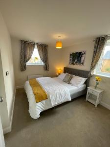 米尔顿凯恩斯Spacious Apartment in Brooklands的一间卧室设有一张大床和两个窗户。
