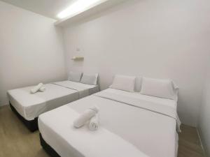 新山Maco Inn Century @Johor Bahru的白色墙壁客房的两张床