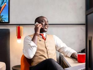 阿比让Ibis Styles Abidjan Plateau的坐在一张桌子上,在手机上说话的男人