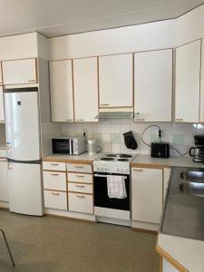 万塔Kotimaailma - Kalustettu saunallinen asunto kuudelle的厨房配有白色橱柜、炉灶和冰箱。
