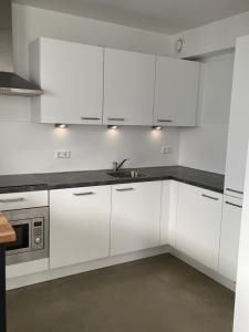 阿纳姆Home sweet home Arnhem的白色的厨房配有白色橱柜和水槽