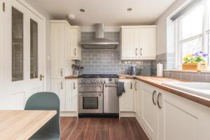 爱丁堡Modern Two Bedroom Apartment, Roseburn, Edinburgh - Free Parking的厨房配有白色橱柜、炉灶和水槽。