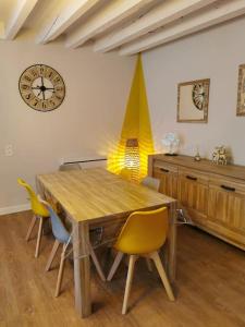 萨尔特河畔弗莱斯涅Maison Chaleureuse dans petite cité de caractère的餐桌、椅子和墙上的时钟