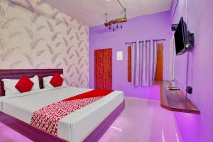马杜赖OYO Flagship Ar Grand的一间卧室配有一张紫色墙壁的床和一台电视。