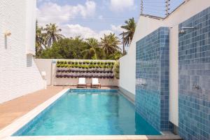 卡姆布库Hotel de Luxo Tango Suites & Coworking Cumbuco的蓝色瓷砖房子内的游泳池