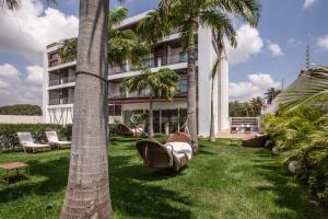 卡姆布库Hotel de Luxo Tango Suites & Coworking Cumbuco的拥有棕榈树的酒店,在院子里设有吊床