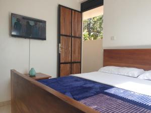 KigoRosa negra kampala的卧室配有一张床,墙上配有电视。