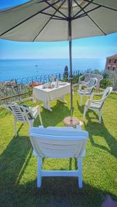 卡莫利Villa Mortola的一张桌子和椅子,配有雨伞和大海