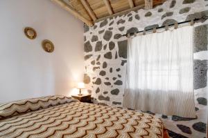 LajidoAdega Maciel的一间卧室设有一张床和一面岩石墙