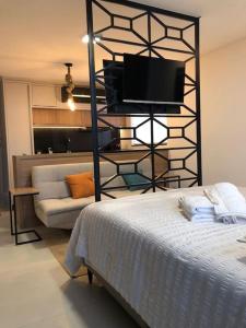 波梅罗迪Lindo Flat Central - Home Business的一间卧室配有一张床、一台电视和一张沙发