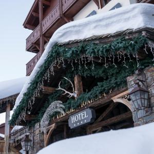 蒂涅Hôtel Village Montana by Les Etincelles的一座积雪建筑前的酒店标志