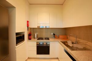 迪拜Stunning Apartment with Direct access to Dubai Mall的厨房配有白色橱柜和炉灶烤箱。