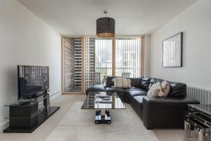 米尔顿凯恩斯City Stay Apartments - Vizion的客厅配有黑色沙发和电视