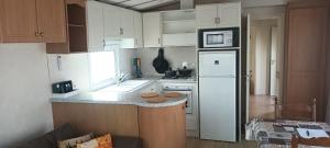 米德尔克尔克cottage Tangro的厨房配有白色橱柜和白色冰箱。