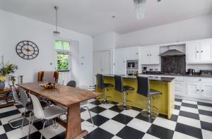 邓迪Westwood Cottage的厨房铺有黑白格木地板,配有木桌。