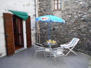 赫拉弗多纳Gravedona Village House的庭院里配有桌椅和遮阳伞
