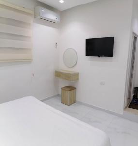 瓦迪穆萨穆萨温泉大酒店 的白色的卧室设有床铺和墙上的电视