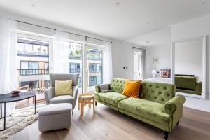 伦敦Modern Chelsea Apartment的客厅配有绿色沙发和两把椅子