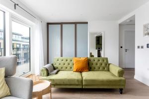 伦敦Modern Chelsea Apartment的客厅配有带橙色枕头的绿色沙发