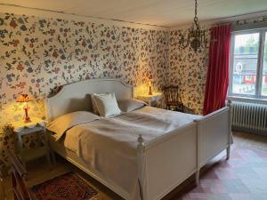 SöderbärkeHandlarens villa - Vandrarhem de luxe的一间卧室配有一张带花卉壁纸的床