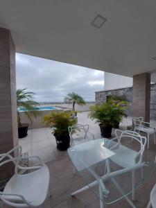 萨利纳斯Oasis Suite Salinas的露台配有白色的椅子和桌子,享有海滩美景