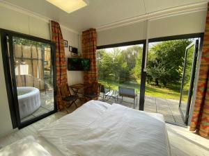 SzakcsJANUS COUNTRY SITE Üdülőházak的一间卧室配有一张床和一个配有浴缸的阳台