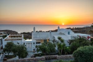 VourvoúlosAnema Boutique Hotel & Villas Santorini的日落在白色房子上,背靠大海
