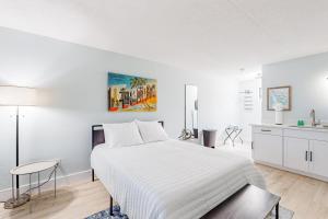 马可岛Capri 107的一间白色卧室,配有一张大床和一个厨房