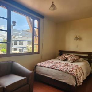 里奥班巴Hotel Bella Casona的卧室配有床、椅子和窗户。