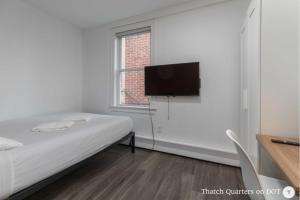 波士顿Quarters on DOT by Thatch的一间卧室配有一张床和一台平面电视