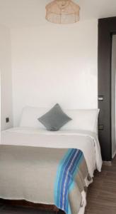 塔哈佐特Oceana Surf Camp的一间卧室配有一张带白色床单和一盏灯的床。