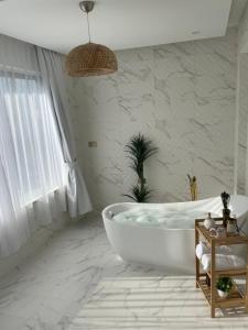 尼兹瓦Al ATLAL apartment的白色的浴室设有浴缸和窗户。