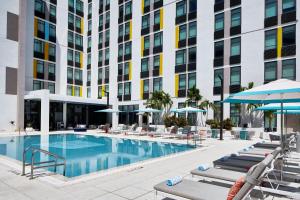 阿文图纳Aloft Miami Aventura的一张酒店游泳池的图片,里面摆放着躺椅和遮阳伞