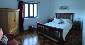 坎普自由鎮Pousada da Vila的一间卧室设有一张床、一个窗口和一把椅子