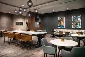 西得梅因West Des Moines Marriott的一间带桌椅和绘画的用餐室