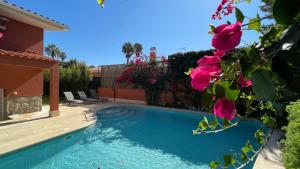 卡斯卡伊斯Studio with Private Swimming Pool and Garden的一座游泳池,位于一个拥有粉红色花卉的庭院内