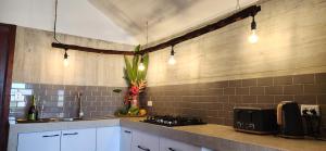 卢甘维尔Bombua Beach House的厨房配有白色橱柜、炉灶和灯具。